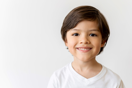 Portrait of a happy Latin American boy looking at the camera smiling over a white background