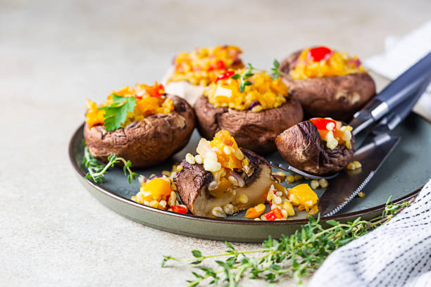 funghi portobello ripieni al forno con pilaf di bulgur e verdure tritate. piatto vegetariano delizioso e nutriente. messa a fuoco selettiva. - edible mushroom stuffed portabello mushroom vegetarian food foto e immagini stock