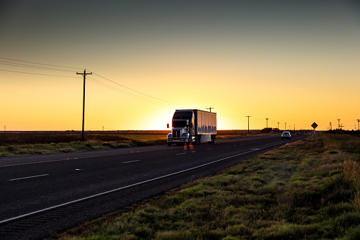Semi-truck on a lonely highway in Texas at sunset.