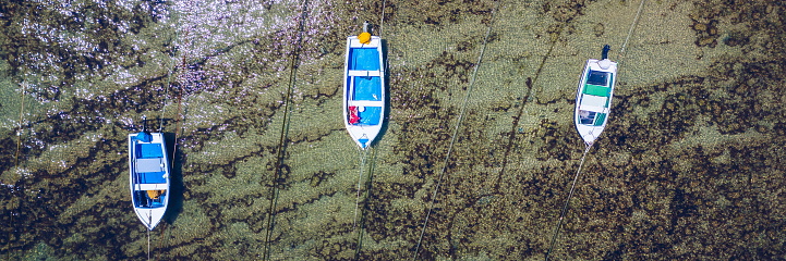 Vintage wooden boat in coral sea. Boat drone photo. Fishing boats in clear turquoise ocean, top view. Small fishing boat moored in blue clean transparent water. Aerial view. Peniche, Portugal.