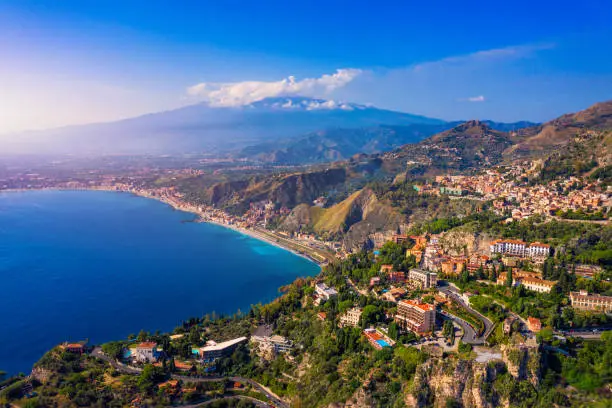 Photo of Taormina is a city on the island of Sicily, Italy. Mount Etna over Taormina cityscape, Messina, Sicily. View of Taormina located in Metropolitan City of Messina, on east coast of Sicily island, Italy.