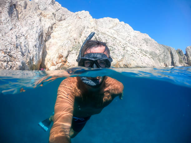 istock Man snorkeling over under photo 1271416467