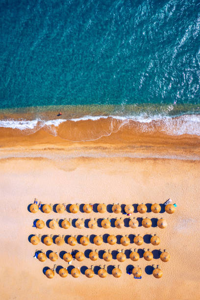 View from above, stunning aerial view of an amazing beach with beach umbrellas and turquoise clear water. Top view on sun loungers under umbrellas on the sandy beach. Concept of summer vacation. View from above, stunning aerial view of an amazing beach with beach umbrellas and turquoise clear water. Top view on sun loungers under umbrellas on the sandy beach. Concept of summer vacation. beach umbrella aerial stock pictures, royalty-free photos & images