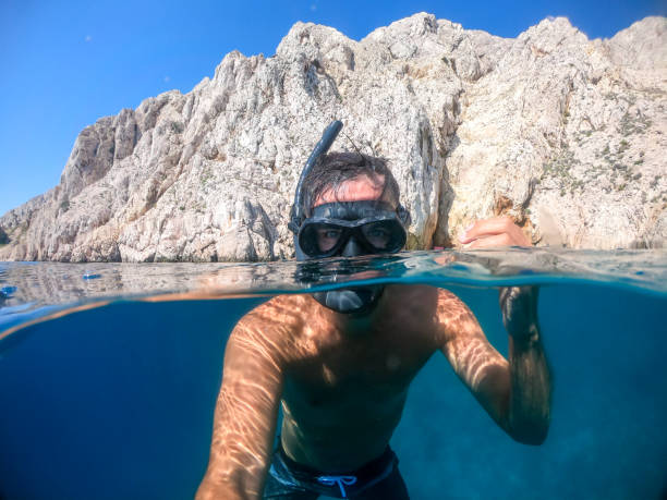 istock Man snorkeling over under photo 1271417259