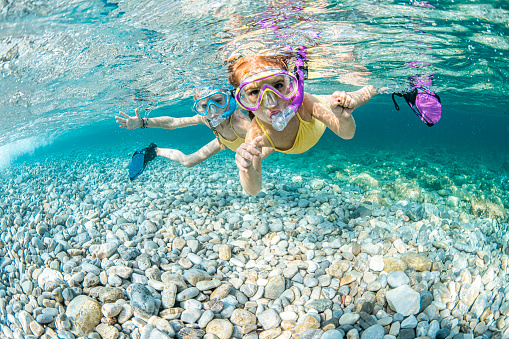 Kids enjoy underwater fun during snorkeling with their colorful masks and fins.