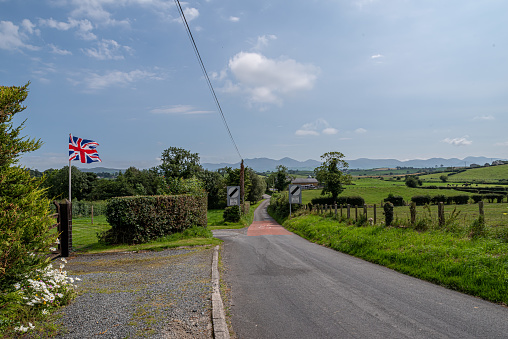 Katesbridge, Northern Ireland, United Kingdom - August 15, 2020: A union jack (British flag) flying by the entrance of a farm, adjacent to a rural road that leads in the direction of the Mourne Mountains (County Down).