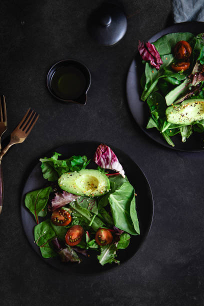 flat lay of green salad on black background - kale vegetable food leaf vegetable imagens e fotografias de stock