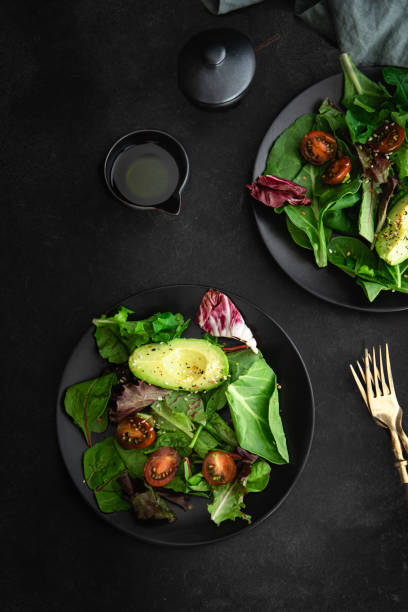 istock Flat lay of green salad on black background 1271422267