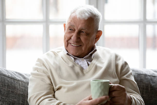istock Happy older man relaxing on sofa with cup of coffee. 1271431618