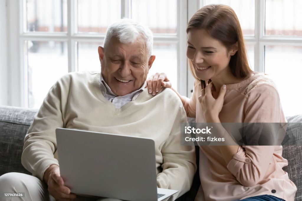 Happy different generations family watching film on computer. Happy different generations affectionate family having fun indoors, looking at laptop screen, enjoying watching funny comedian movie or recollecting memories with vacation photos on electronic device. 35-39 Years Stock Photo