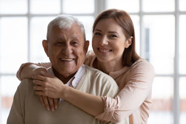 Head shot portrait of smiling young woman cuddling old father. Head shot portrait of smiling affectionate loving grown up daughter cuddling devoted old senior father indoors. Caring young woman enjoying tender free weekend moment with retired daddy at home. father daughter 80s stock pictures, royalty-free photos & images