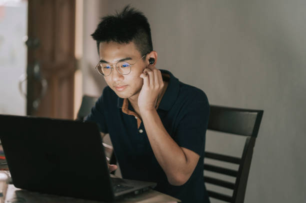 asian chinese teenage boy listening to music with bluetooth earphone and laoptop at home - chinese ethnicity audio imagens e fotografias de stock