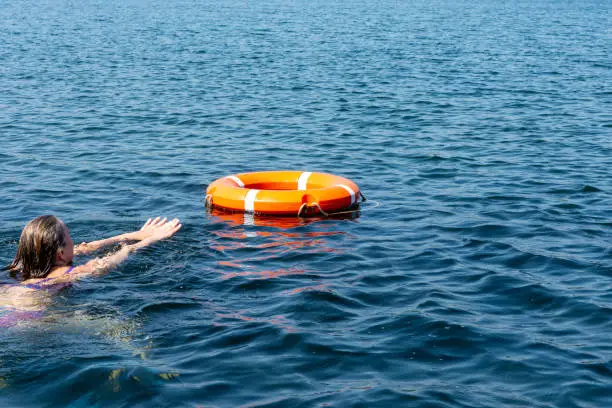 A person in the water gets a lifeline to help. The concept of saving drowning on the water.
