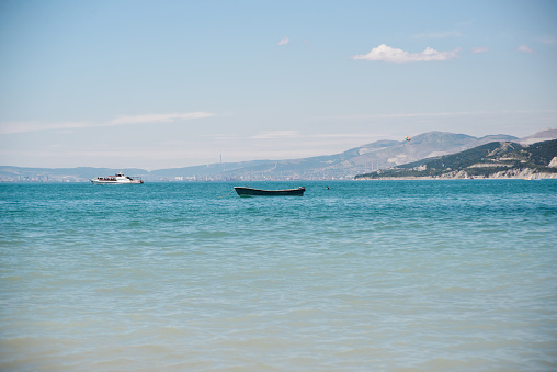 empty wooden boat with no people in bay sea with sky and mountain background, horizontal stock photo image backdrop