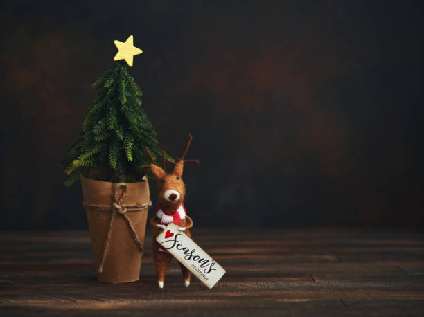 istock Cute Christmas Background with Tree and Felt Reindeer Holding Holiday Greeting 1271445948
