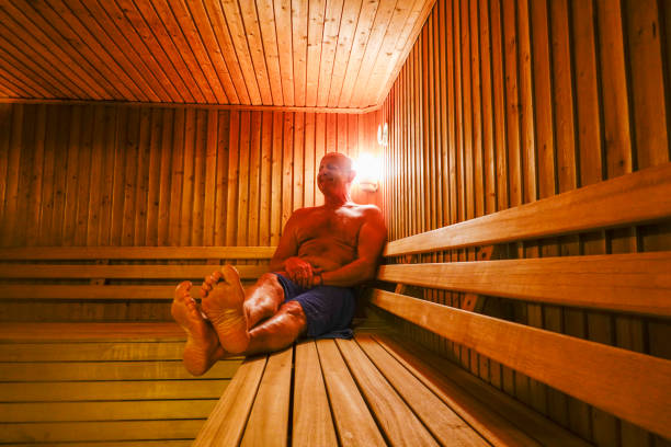 Man in sauna. A middle-aged grimaces from the heat inside of a sauna. swedish sauna stock pictures, royalty-free photos & images