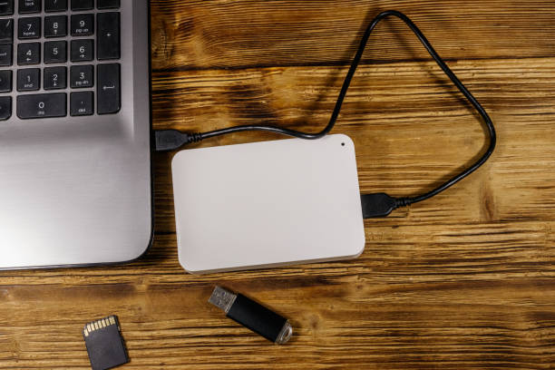 istock External HDD connected to laptop computer, SD memory card and USB flash drive on a wooden desk. Top view. Concept of data storage 1271452596