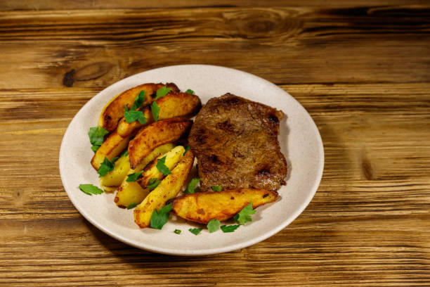 木製のテーブルにポテトウェッジとフライビーフステーキ - sirloin steak baked potato beef gourmet ストックフォトと画像