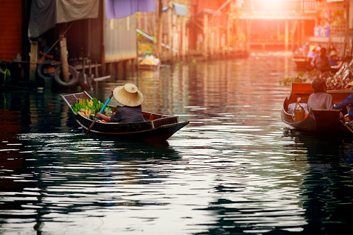 29th January, 2016 - Bangkok, Thailand: Bustling with activity, the floating market in Bangkok is a vibrant mosaic of colors and sounds. Market traders skillfully navigate their boats, laden with a variety of local produce and goods, while boat excursion operators guide tourists and local buyers through the waterways. The scene is a lively showcase of traditional Thai commerce and culture, with visitors engaging in the unique experience of shopping on water.