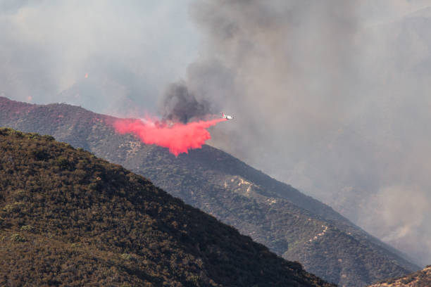 istock Air tanker firefighting aircraft dropping water on a hill on fire 1271459086