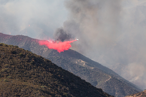 At 0% containment, the fire has burned more than 10,000 acres as of Tuesday night with red flag warnings issued due to the windy conditions. Air tanker firefighting aircraft dropping water on a hill on fire. Super Scooper amphibious firefighting aircraft picking up water from a lake. \