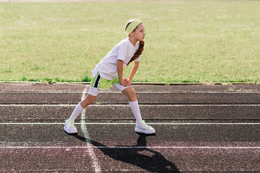 Girl jogging on a sunny summer evening, laying on treadmill, stadium, physical training, back to school, tired.