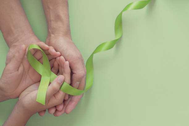 Adult and child hands holding Lime Green Ribbon on green background, children Mental health awareness and Lymphoma Awareness, world mental health day, world kidney day Adult and child hands holding Lime Green Ribbon on green background, children Mental health awareness and Lymphoma Awareness, world mental health day, world kidney day lymphoma photos stock pictures, royalty-free photos & images