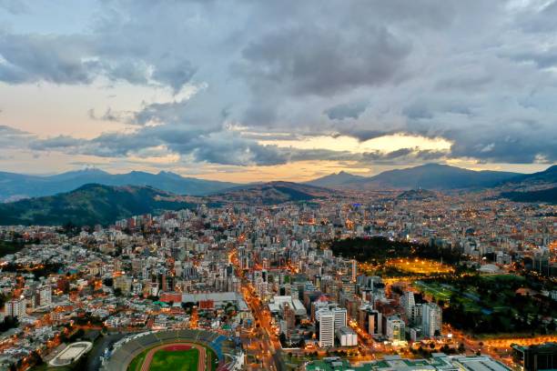 Aerial view of Quito city during sunset Aerial view of a city skyline during sunset, street lights-on and Cotopaxi volcano on the background quito photos stock pictures, royalty-free photos & images