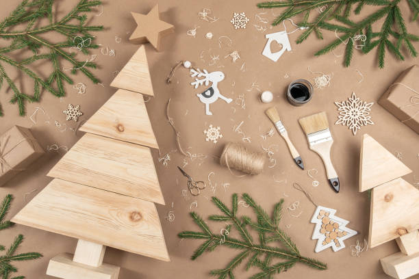 XMAS or New Year composition. Wooden Christmas trees, paint, brushes and fir branches on craft beige background. Concept Zero waste, eco - friendly Merry Christmas. Top view Flat lay stock photo