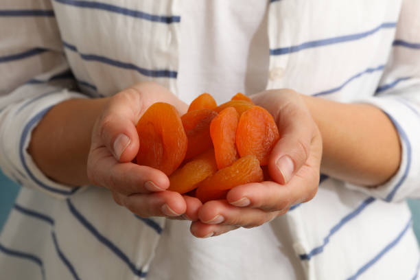 여자는 맛있는 말린 살구를 잡고, 닫습니다 - dried apricot 뉴스 사진 이미지