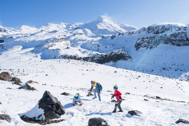 Mixed race kids enjoying outdoors playing with snow having fun at Mt Ruapehu, National Park, New Zealand.