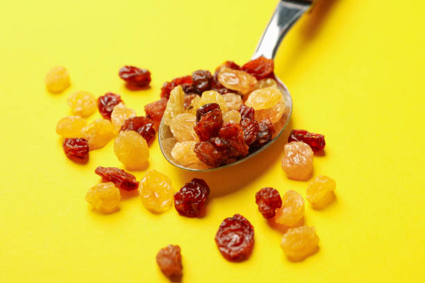 istock Spoon with raisins on yellow background, close up 1271471910