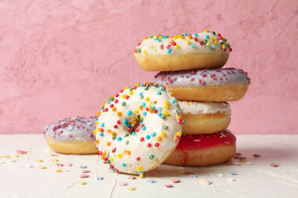 istock Tasty donuts on white table against pink background 1271472630
