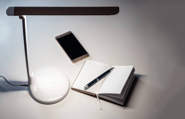 istock A smartphone and open diary with a pen on the table under the desktop LED lamp 1271472698