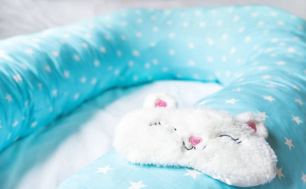 istock Light blue supporting pillow with stars on white sheet in bed for comfortable sleep of pregnant woman. Funny sleeping mask in form of bunny,cat with eyes,ears,mouth. Accessories for expectant mothers 1271472785