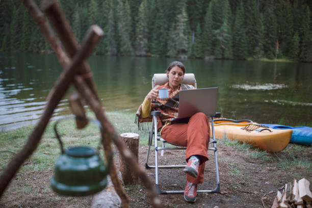istock Beautiful Brunette Female Is Working Next To The Camp Fire During Her Camping vacation 1271472844