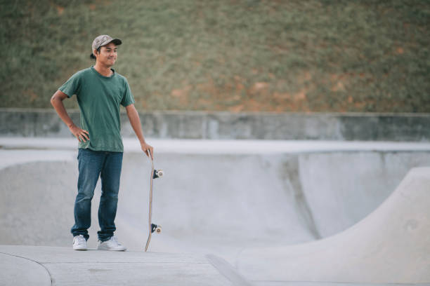 istock Asian skateboarder looking at his partner playing and taking a break 1271473138