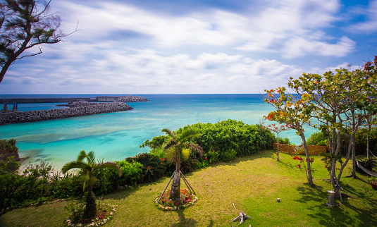 A long exposure shot of a stunning Okinawa beach. Clouds are showing movement and the ocean is totally flat and calm due to the long exposure.