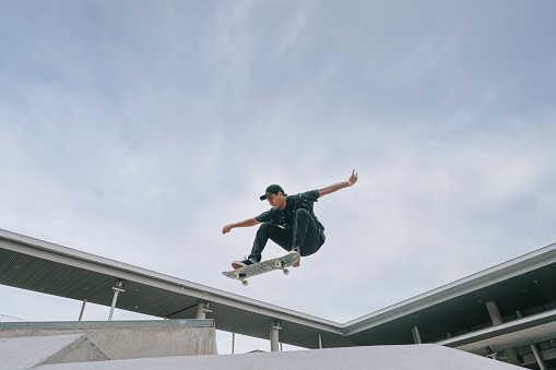 Asian skateboarder in action mid air