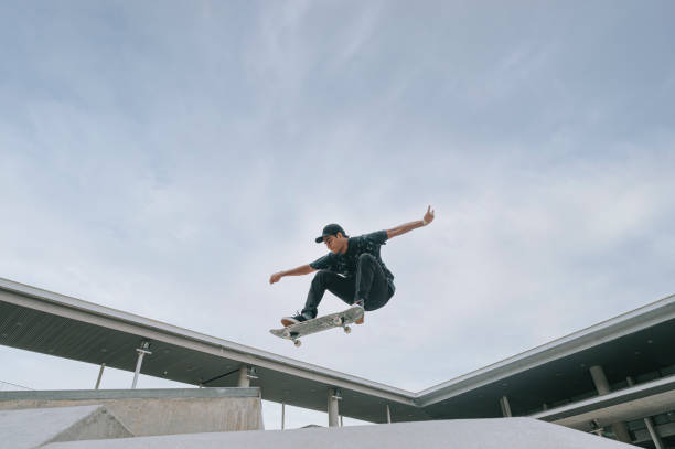asian skateboarder in action mid air - directly below fotos imagens e fotografias de stock