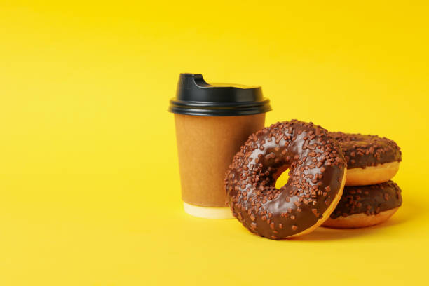 istock Paper cup and tasty donuts on yellow background 1271474314