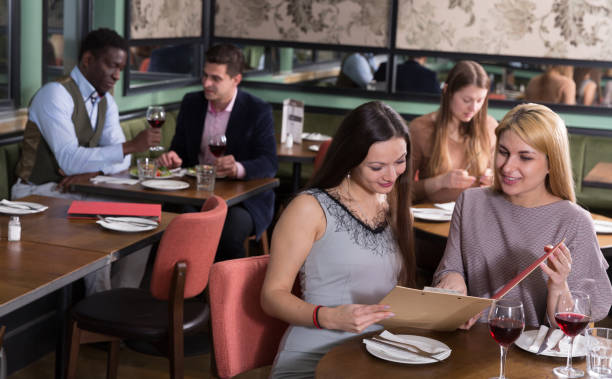 istock Two female friends with menu card in restaurant 1271479810