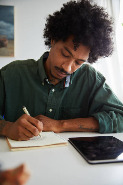istock Young artist sitting in his studio and drawing in a sketchbook 1271481012