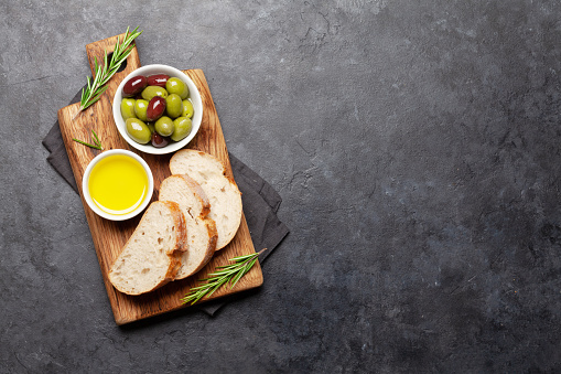 Ripe olives, olive oil and ciabatta bread. Top view flat lay with copy space