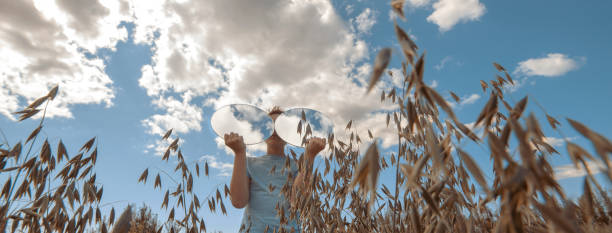 istock A boy with two round mirrors, in which the sky is reflected in glasses, stands in a field of wheat 1271484231