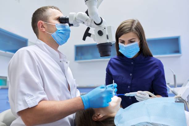 치과 현미경 기기를 사용하여 치아를 치료하는 남성 의사 치과 의사 - dentists chair chair dentist office stomatology 뉴스 사진 이미지