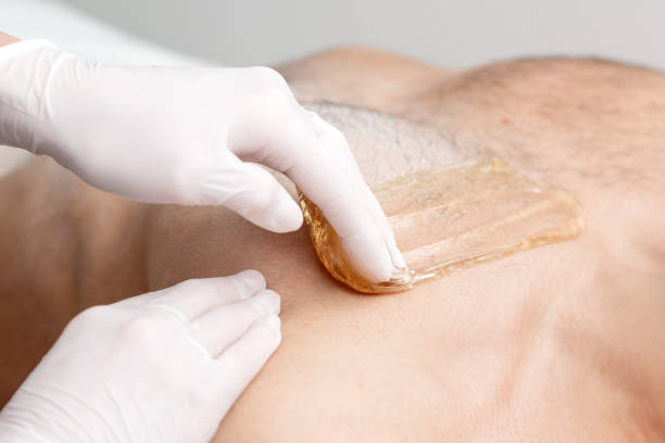 Epilation chest of young male Epilation chest of young male with liquid wax paste by hands of female cosmetologist in beauty salon half dressed girls pictures stock pictures, royalty-free photos & images