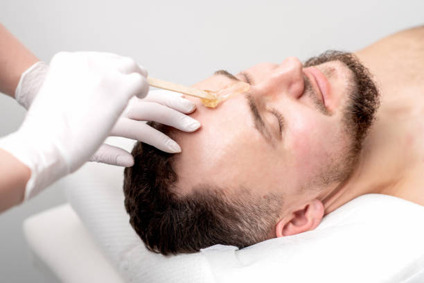 Beautician applies wax between male eyebrows Beautician applies wax between male eyebrows before the procedure of waxing in the beauty salon wax stock pictures, royalty-free photos & images