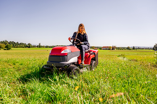 Young woman driving a tractor on a lawn