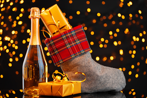 Champagne bottle and Christmas stocking with gifts against garland